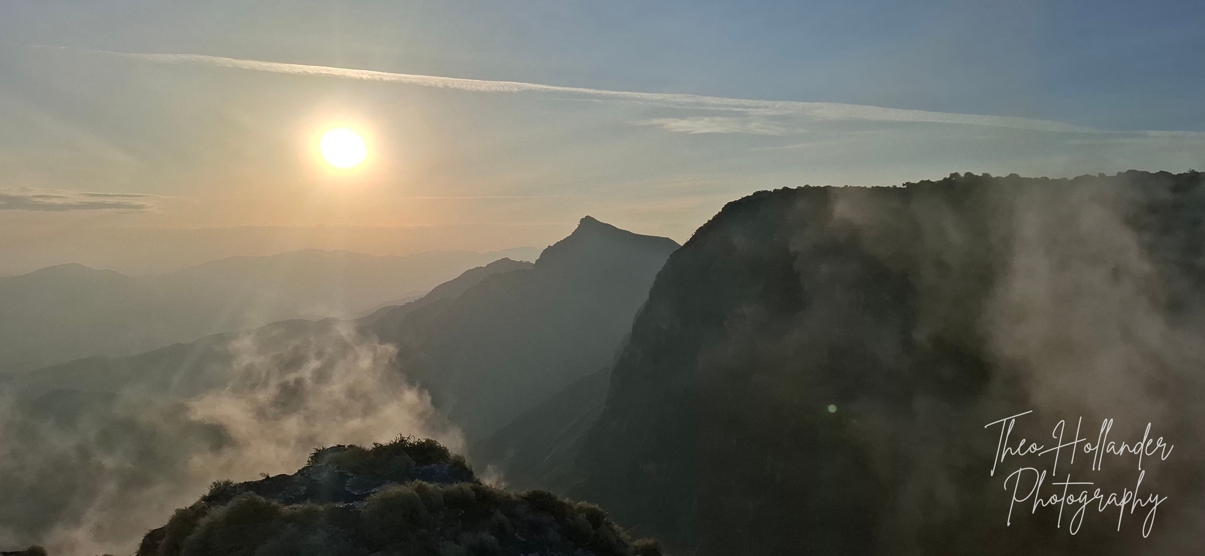 Sunrise breaking through mist over a mountain ridge