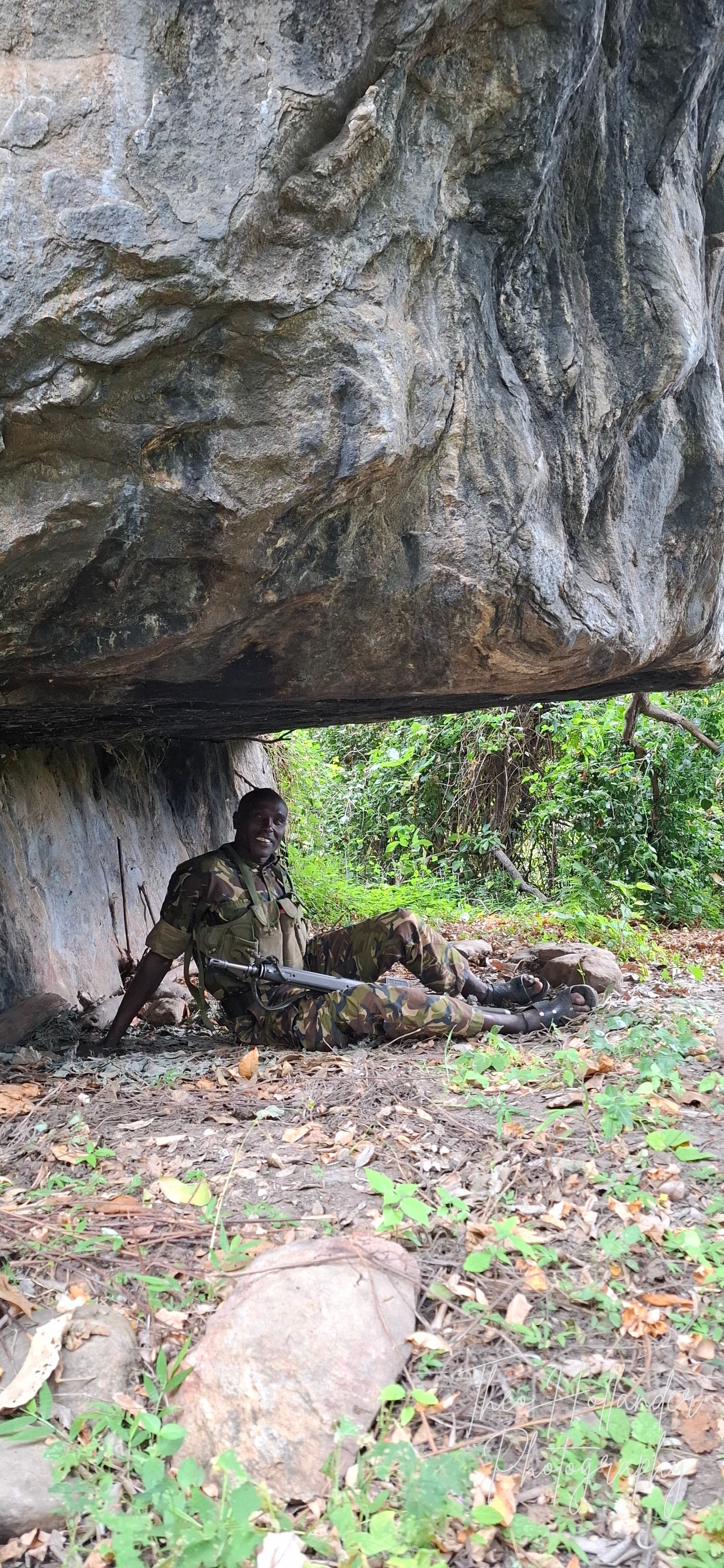 A ranger resting in the shade of a rock shelter