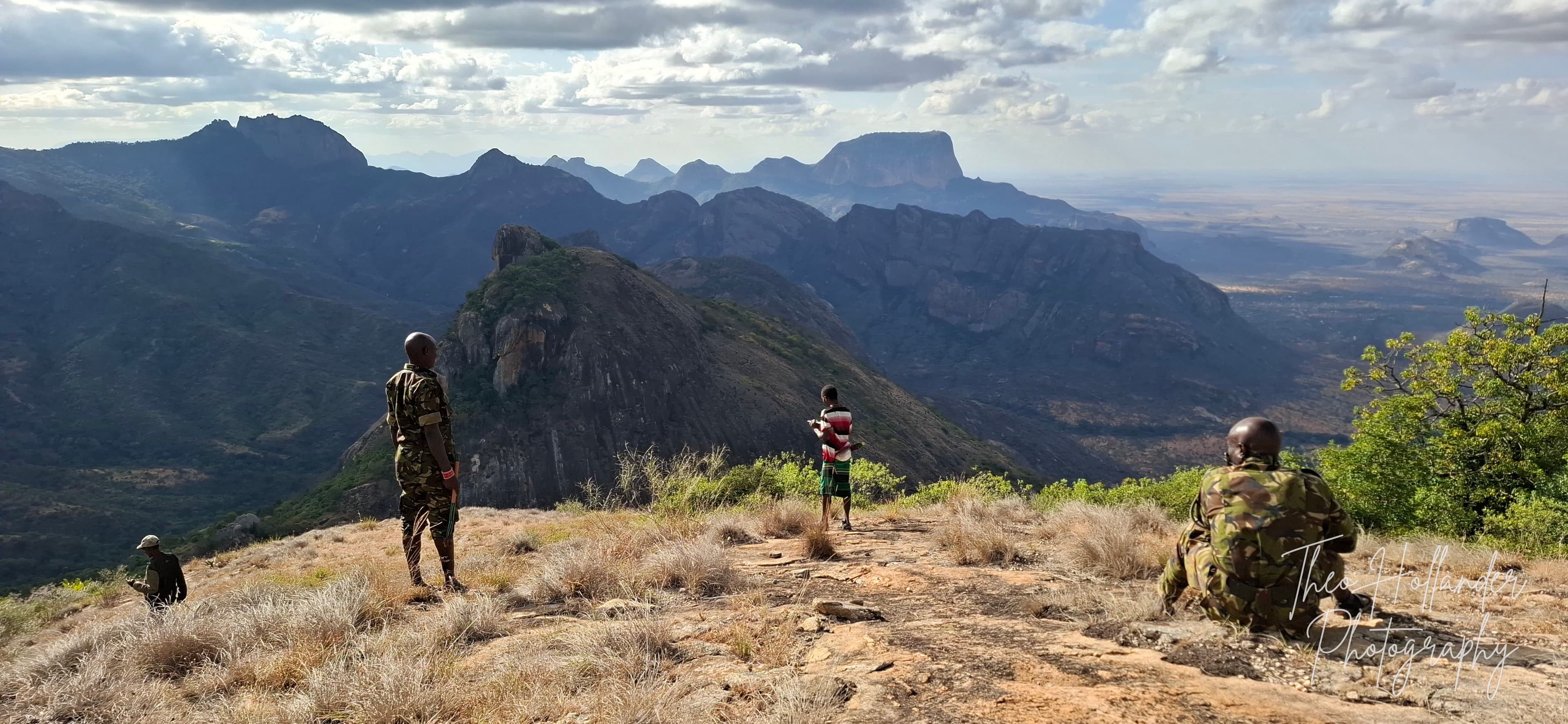Armed rangers surveying the valley from a ridge viewpoint
